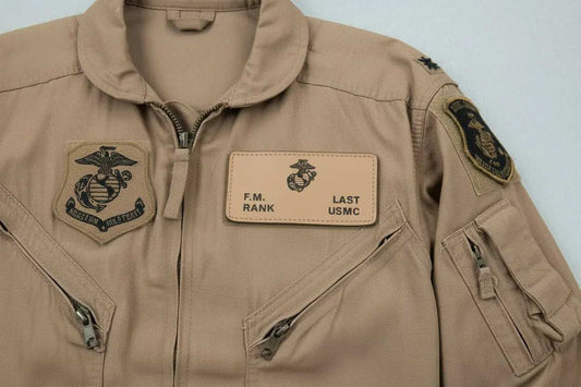 Marine flight jacket with tan fabric, black embroidered sleeve and chest insignia, and a tan name patch reading F.M. RANK; Leather flight badges, Marine Badges